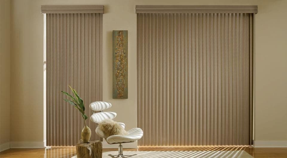 Taupe vertical blinds covering wide and narrow glazing beside a white chair